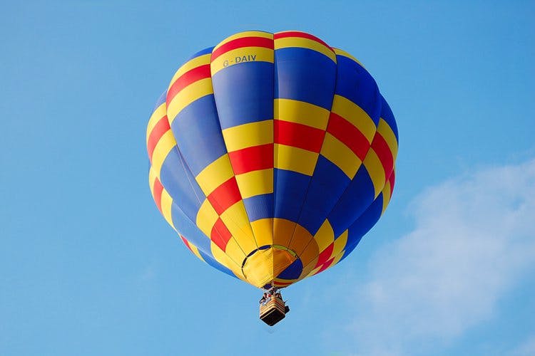 Hot air balloon,Hot air ballooning,Air sports,Sky,Balloon,Daytime,Air travel,Yellow,Blue,Vehicle