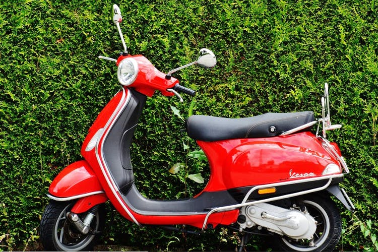 Vehicle,Motor vehicle,Red,Scooter,Car,Moped,Motorcycle,Grass,Automotive design,Plant