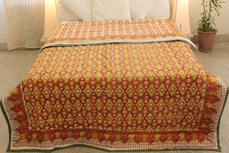 Bed sheet,Orange,Bedding,Quilting,Textile,Yellow,Quilt,Floor,Linens,Furniture