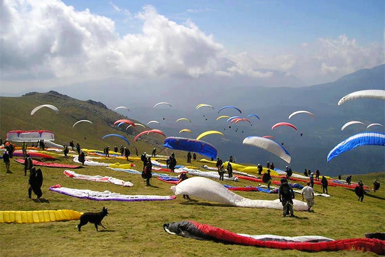 Paragliding,Air sports,Windsports,Cloud,Parachute,Sky,Grassland,Wind,Mountain range,Sports