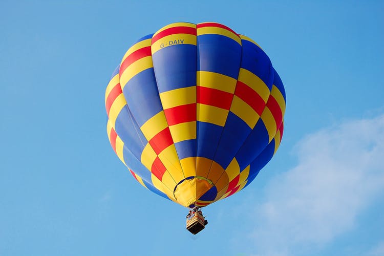 Hot air balloon,Hot air ballooning,Air sports,Air travel,Balloon,Daytime,Sky,Yellow,Blue,Vehicle